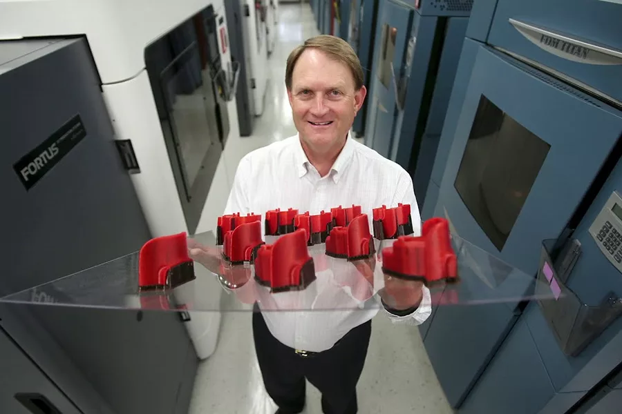 Scott Crump holds tray of 3D printer items.
