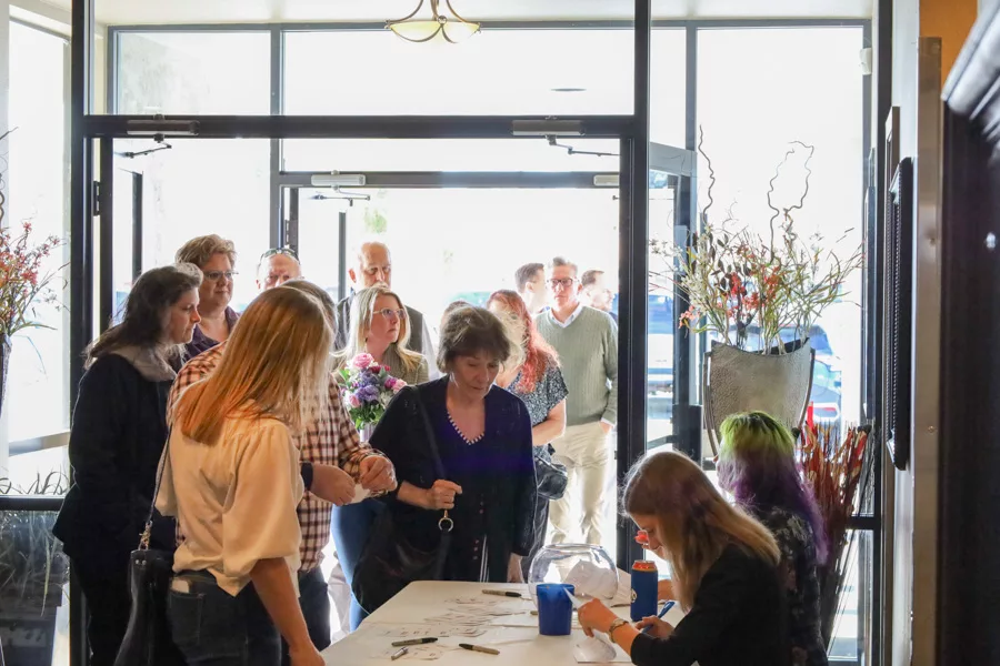 People lining up at a sign in desk.