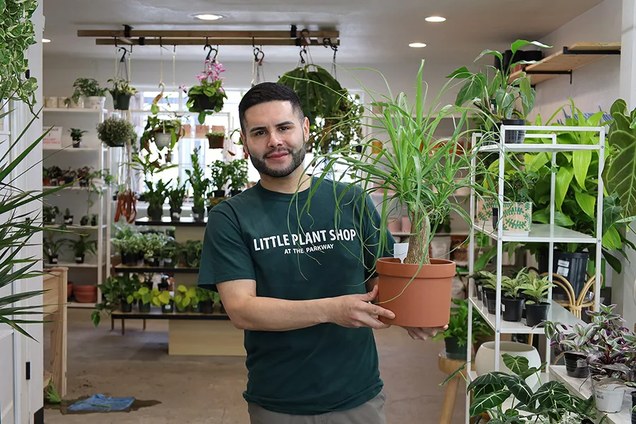 Jose Chavez holding a potted plant inside the shop.