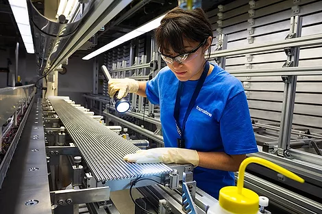 A worker inspecting rods with a flashlight.