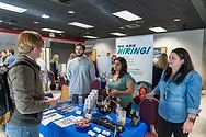 A student talking to people behind a booth at a job fair.