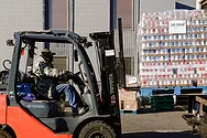 A forklift carrying a pallet of cans.
