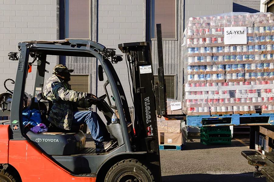 A forklift carrying a pallet of cans.