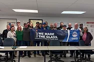 People holding a banner that says, "WE MADE THE GLASS."