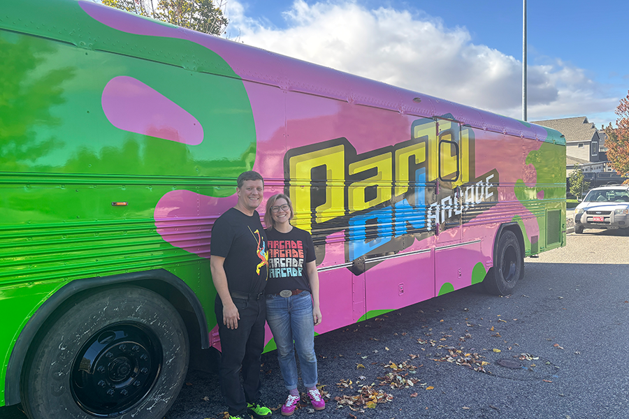 Two people standing outside a bus.