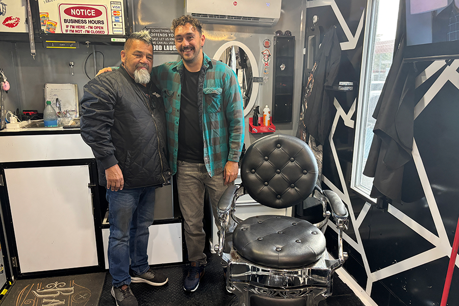 Two people standing inside a barbershop.
