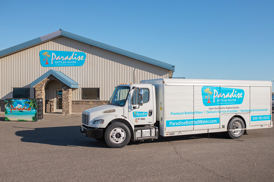 A building and a truck that both say, "Paradise Bottled Water".