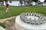 A large concrete base in a front yard with a person looking at it.