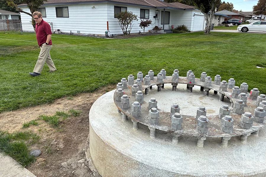 A large concrete base in a front yard with a person looking at it.