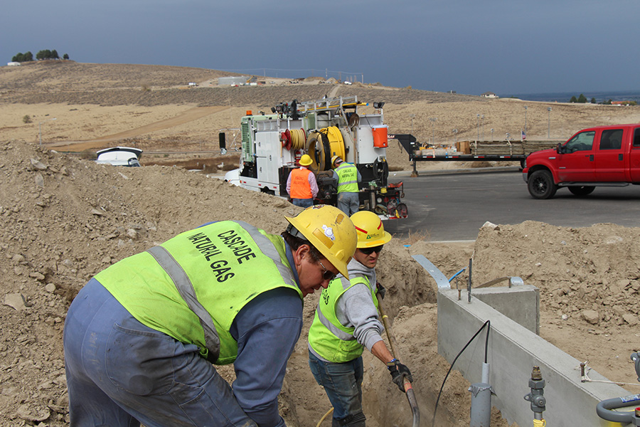Workers in dirt installing gas lines.
