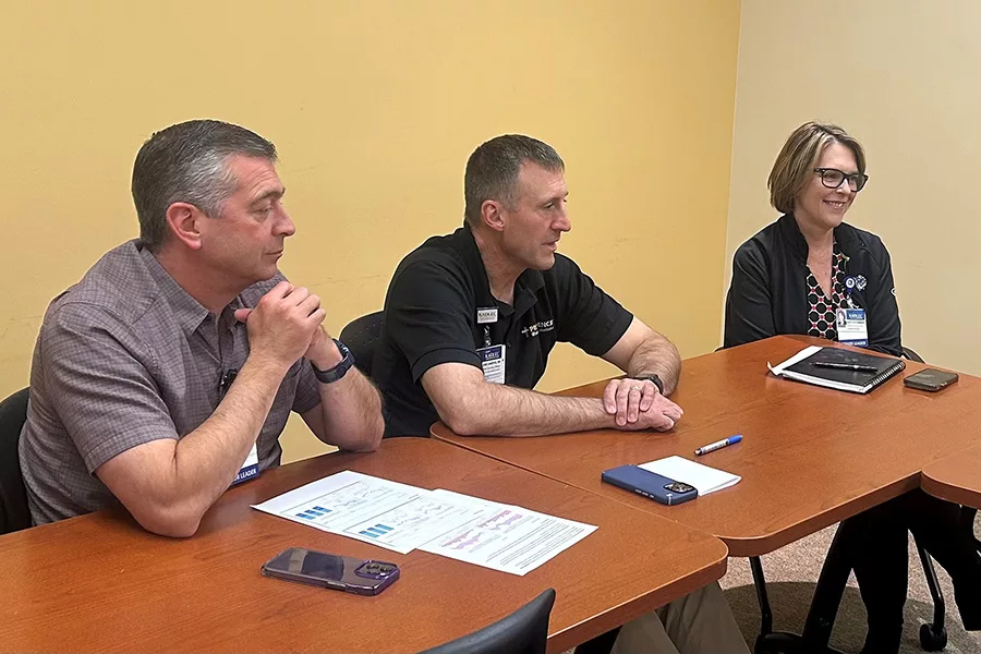 3 people sitting at a desk.