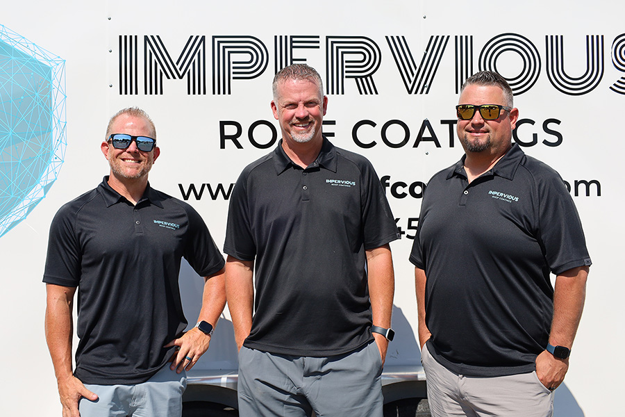 Three men standing near the Impervious logo.