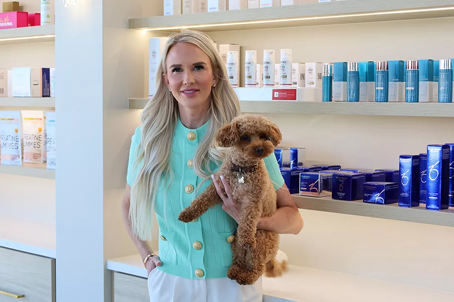 A woman holding a dog near shelves of product.