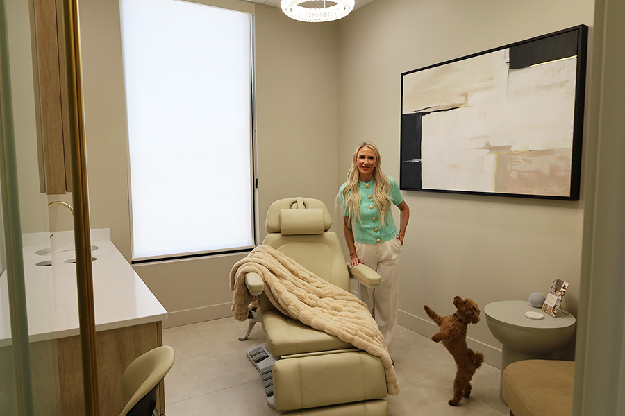 A woman standing in a room with a big chair and two small dogs.