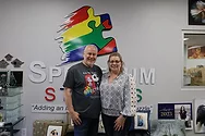 Two people standing in front of a wall with the Spectrum Studios logo.