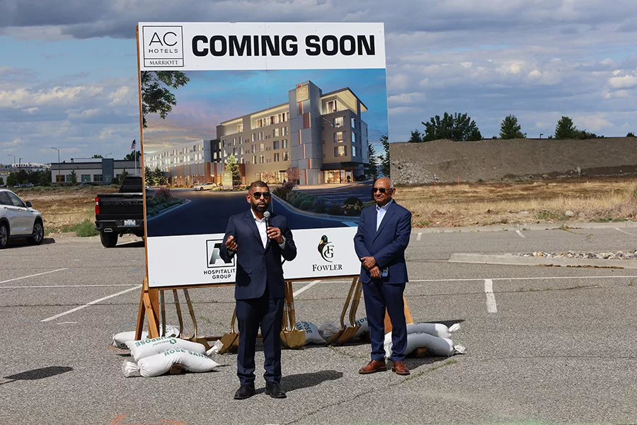 People standing next to a large coming soon billboard.
