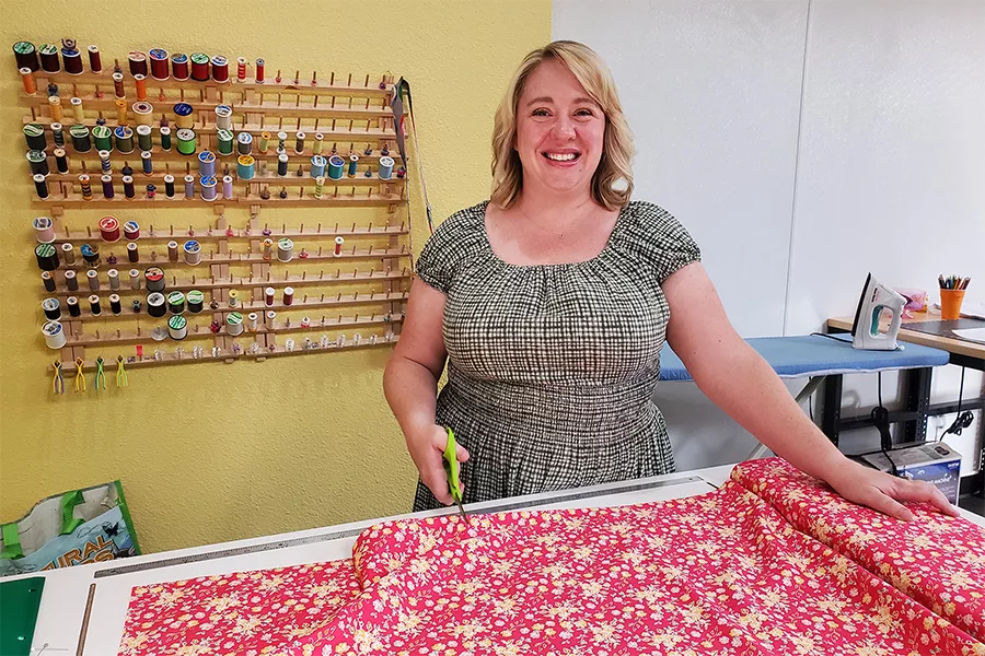 A woman standing with fabric and scissors.