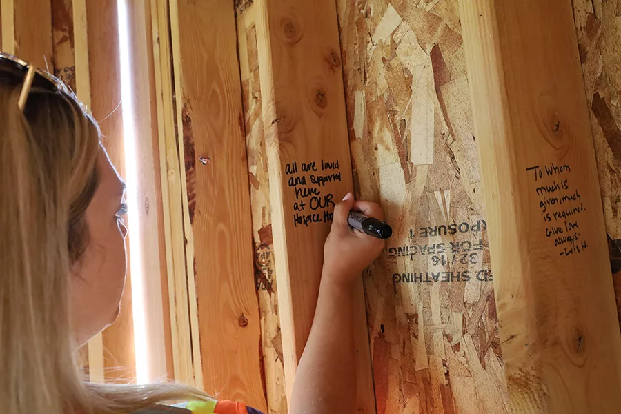 Someone writing a message on a stud. The message reads, "all are loved and supported here at our Hospice House".