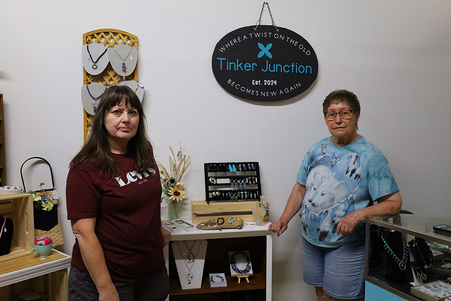 Two women standing near a sign that reads, "Tinker Junction".