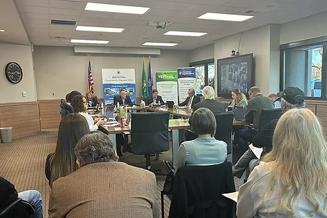 A room of people around a desk.
