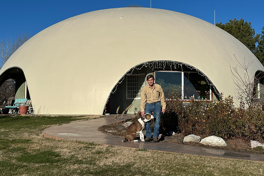 A man with a dog next to a dome house.