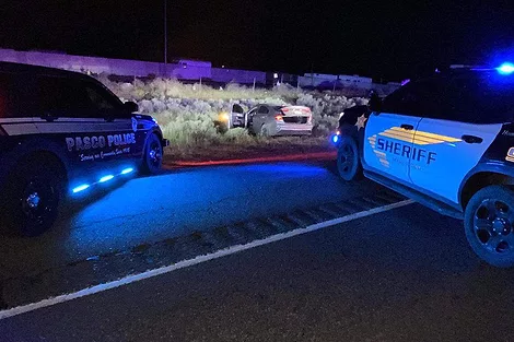 A car off the side of the road with police cars nearby.