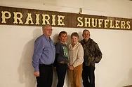 People standing next to Prairie Shufflers sign.