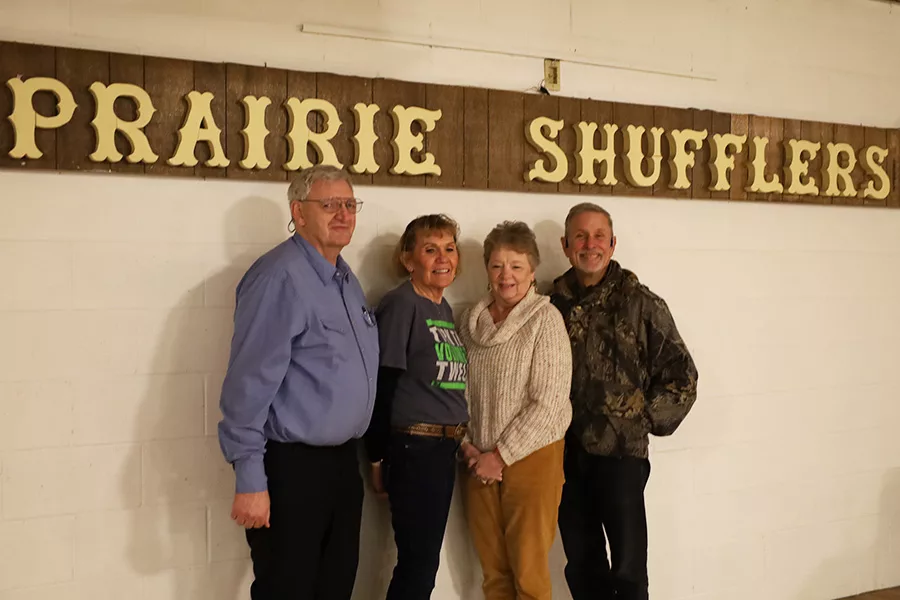 People standing next to Prairie Shufflers sign.