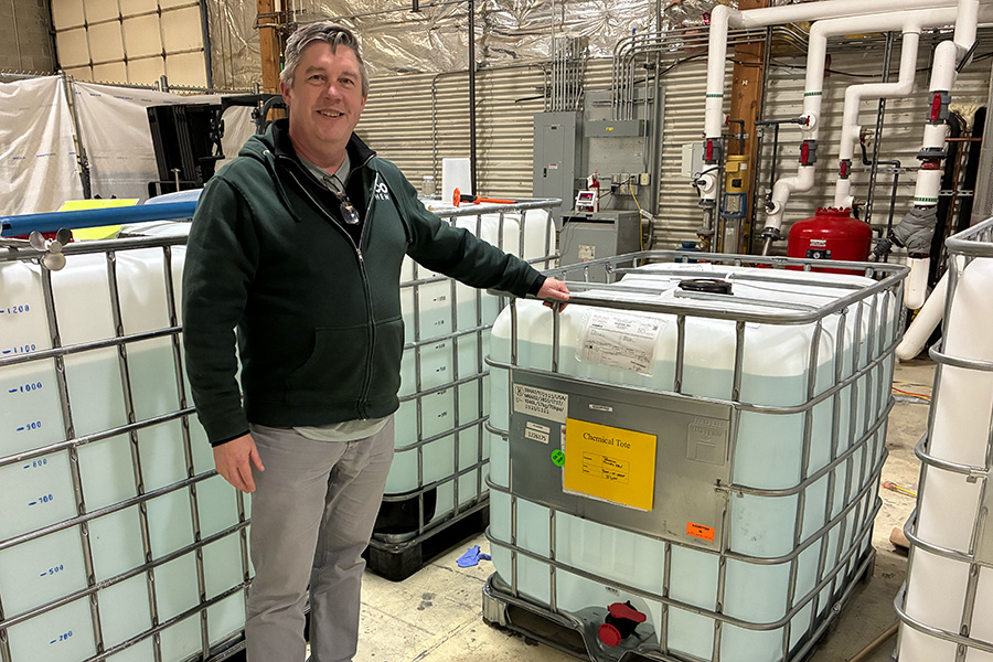 Man standing with big cubic tanks.