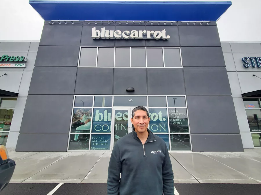 Person standing outside of a building that says, "Bluecarrot".