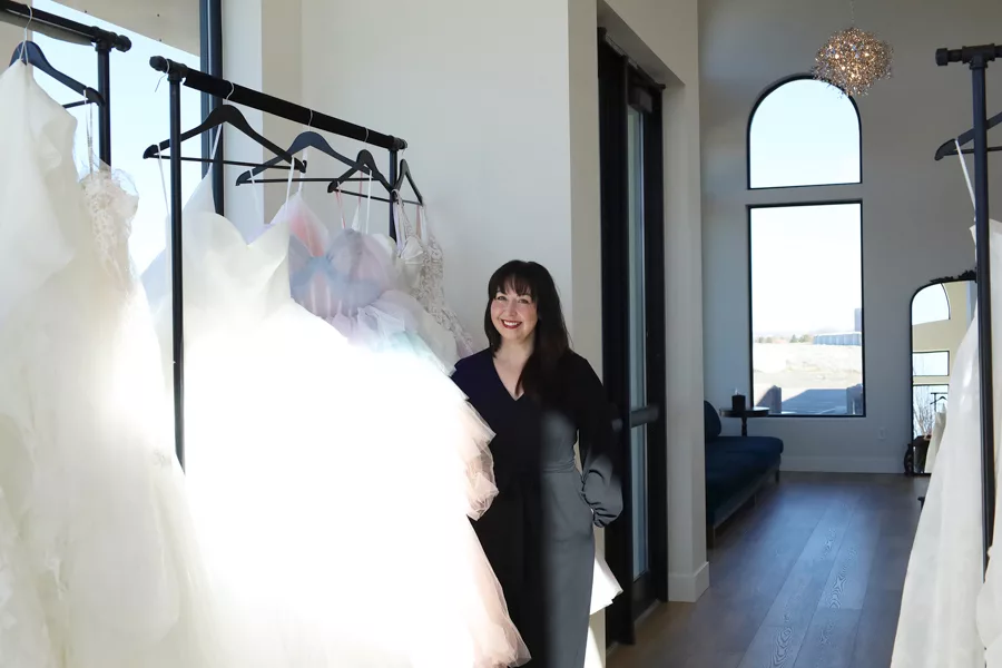 Woman standing with racks of wedding dresses.
