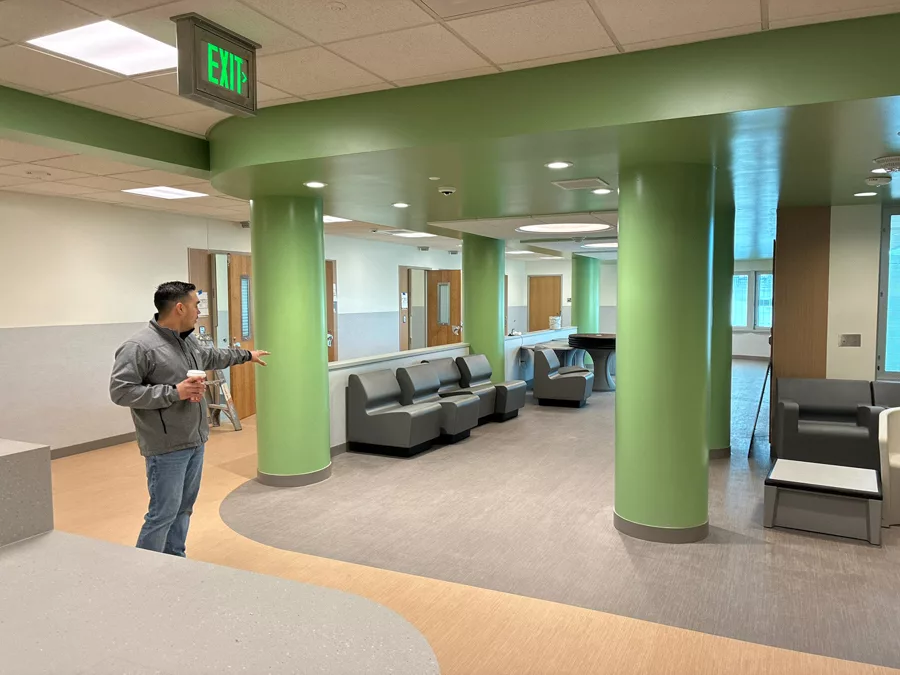 Man showing a space with chairs and pillars.