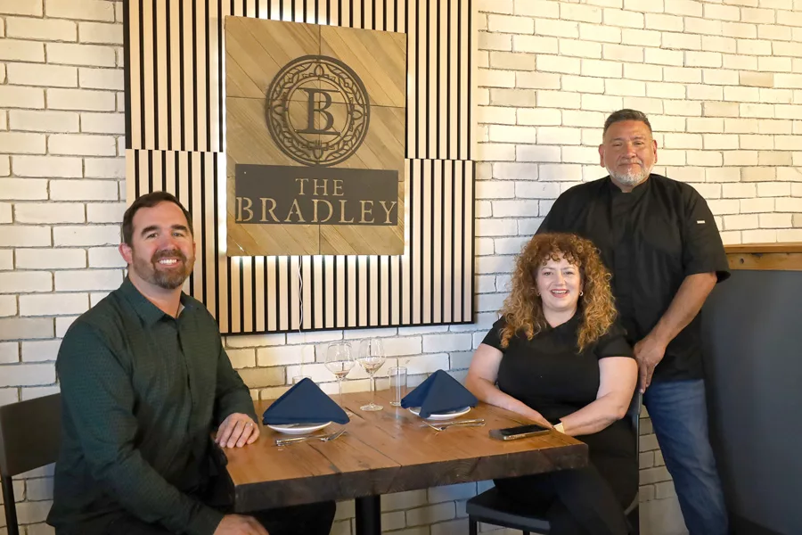 People sitting at a table near a sign that says, The Bradley.
