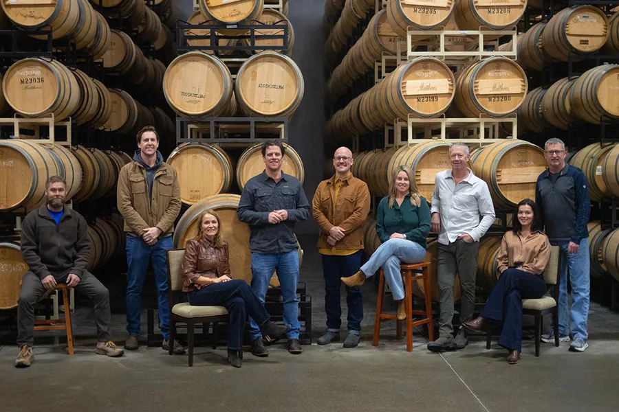 People in front of risers with wine barrels.