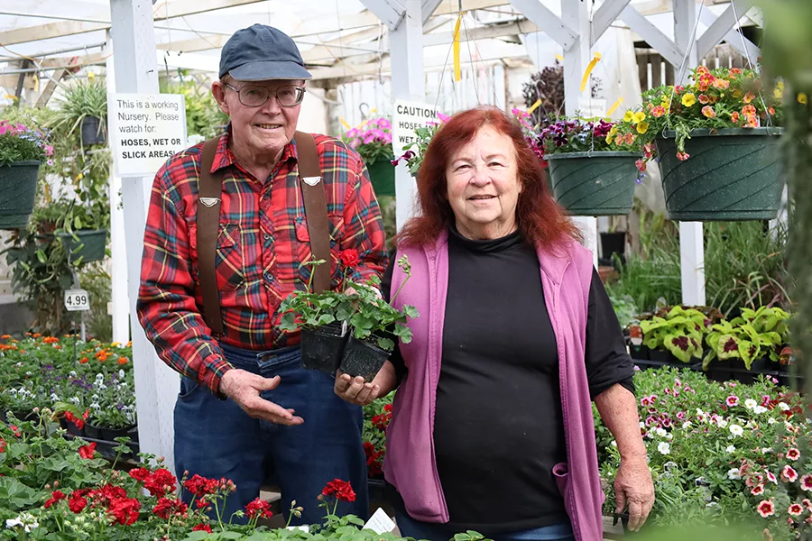 Two people standing in a greenhouse.