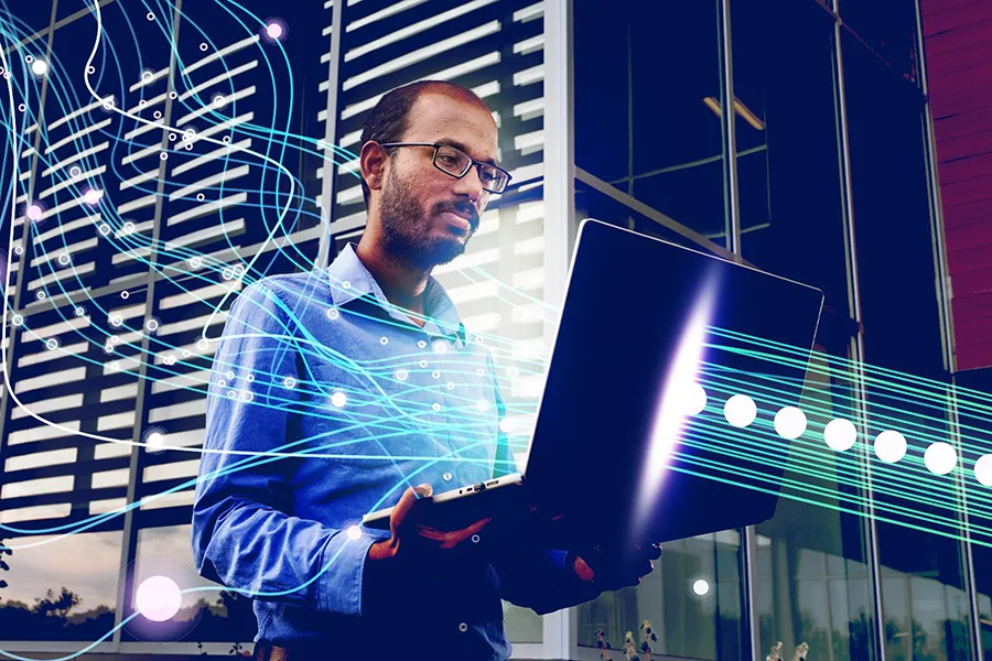 A person on a laptop with technology emanating from their laptop.