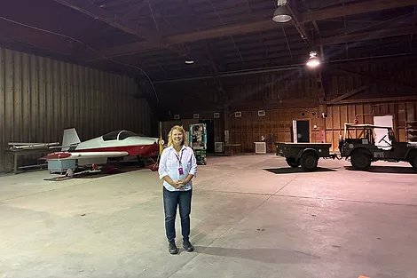 Woman standing in a large empty hangar.