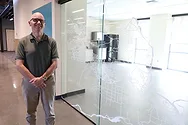 A man standing by a glass decal.