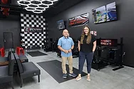 Man and woman in a racing sim room.