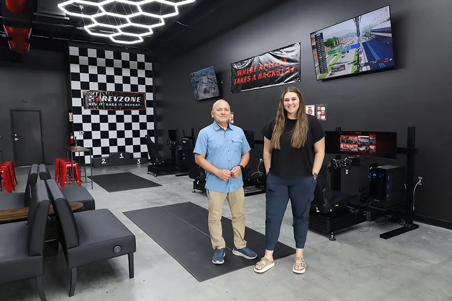 Man and woman in a racing sim room.