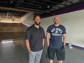 Two men standing in an empty space.