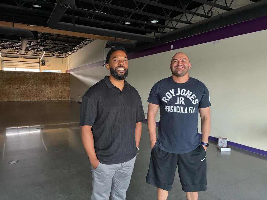 Two men standing in an empty space.