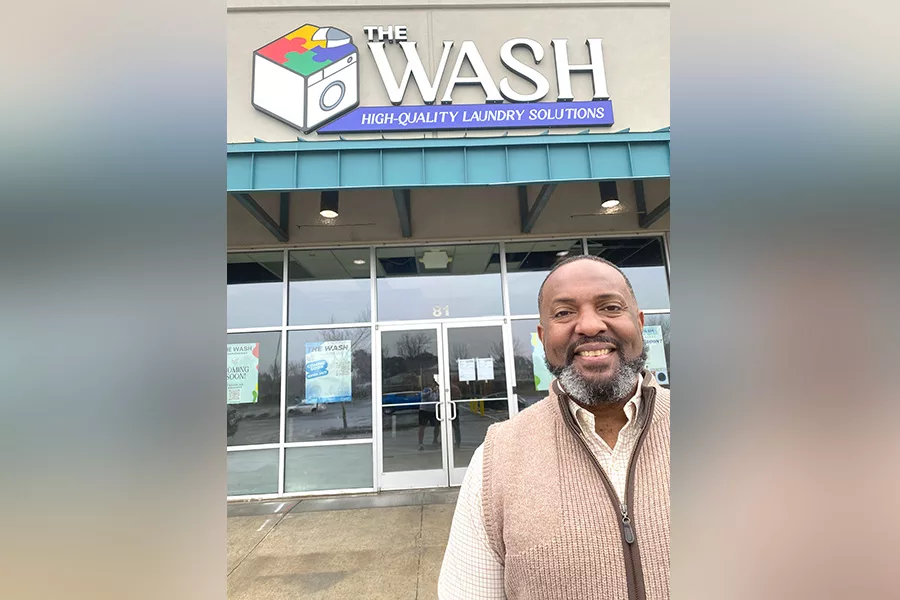 Man standing outside a laundromat called, "The Wash".