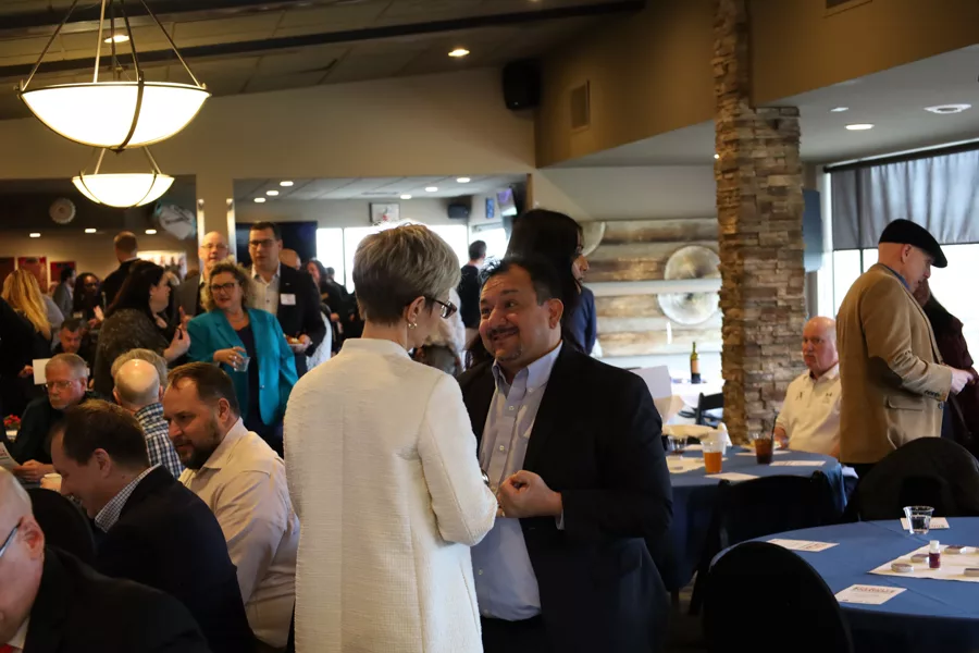 Two people talking with a crowd in the background.