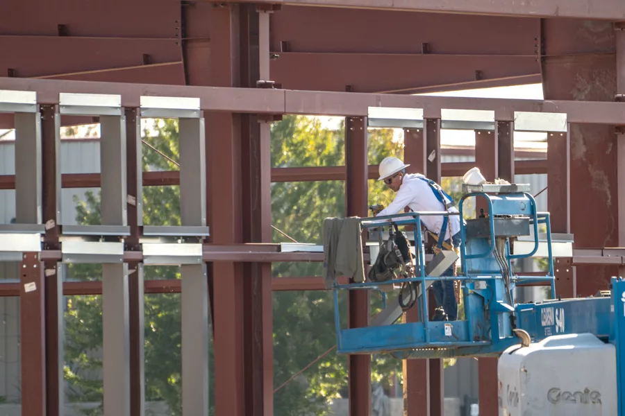 A worker on a lift near some framework.