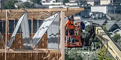 A person on a lift working on some framing.
