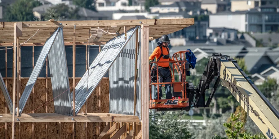 A person on a lift working on some framing.