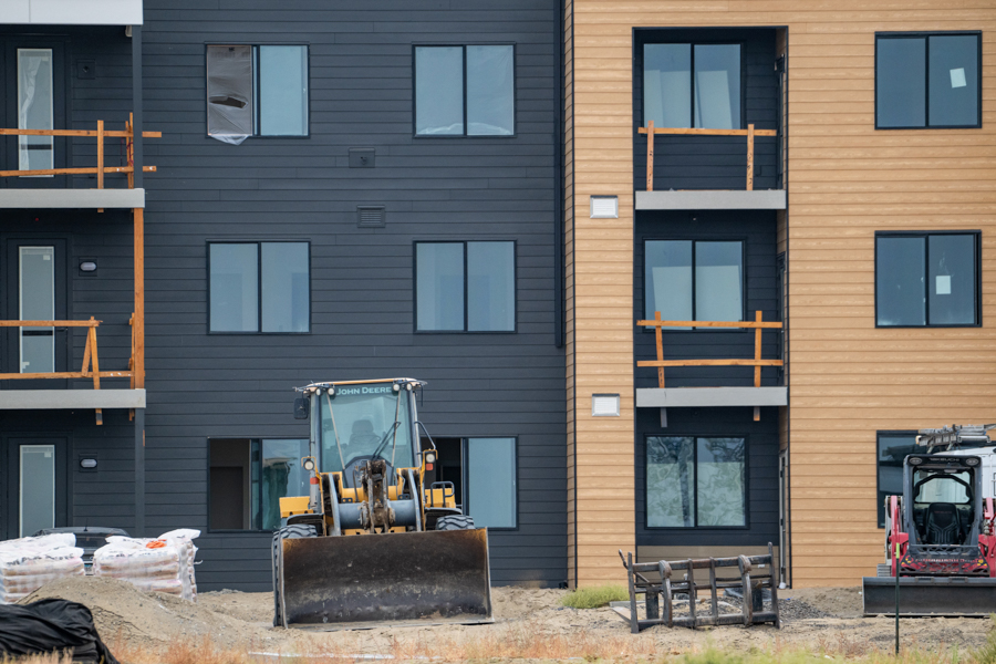 Apartments under construction and earth-moving equipment in the foreground.