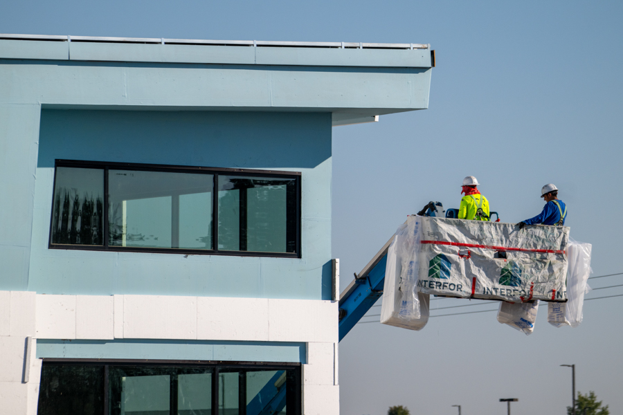 Workers on a lift near a building under construction.
