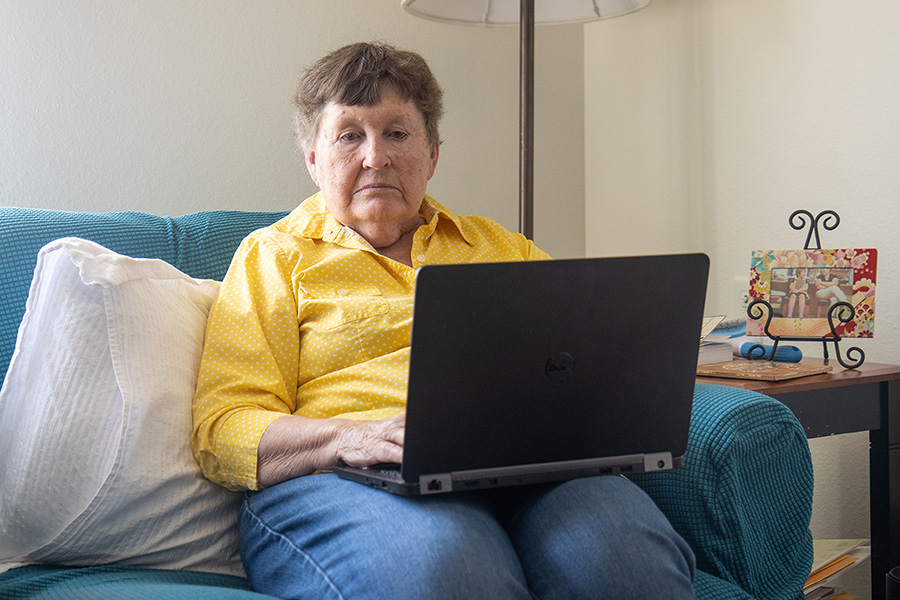 Elderly woman on a couch with a laptop.